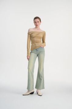 Woman in an off-shoulder top and flared jeans posing in a studio