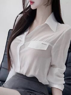 Woman with long dark hair wearing a sheer white shirt and grey skirt