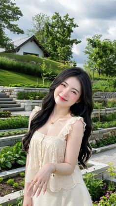 Woman with long black hair and a lace top smiling in a garden