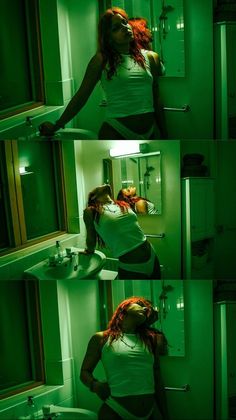 Woman with long red hair in a white tank top and underwear in a green-lit bathroom