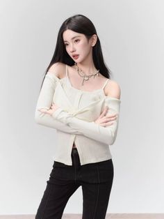 Woman with long black hair wearing an off-shoulder top and black jeans