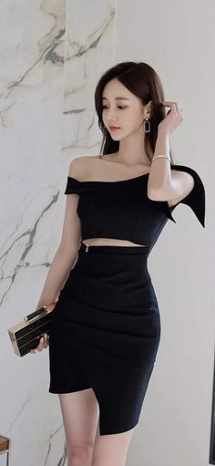 Woman in a black off-shoulder dress with a cutout and a clutch bag