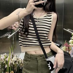 Person in a striped crop top and green pants taking a mirror selfie