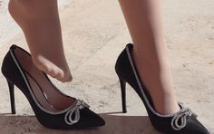 Woman's feet in black high heels with rhinestone bows and nude stockings