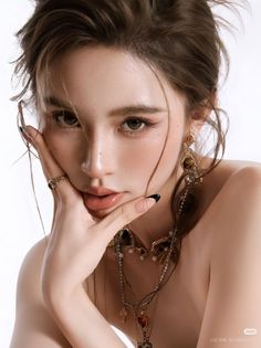 Woman with long hair and jewelry, posing with hand on chin