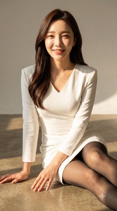 Woman in a white dress and black tights sitting on the floor with soft lighting