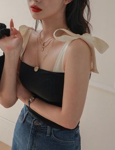 Woman in a black top and denim jeans with layered necklaces and red lipstick