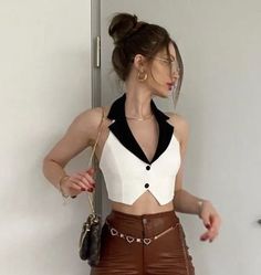 Woman in a white halter top and brown pants with a mini bag