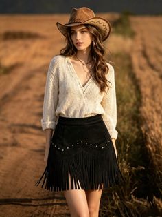 Woman in a cowboy hat and fringe skirt in a field at golden hour