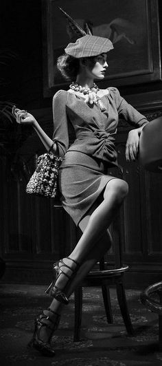 Woman in a plaid hat and dress with strappy heels, sitting indoors