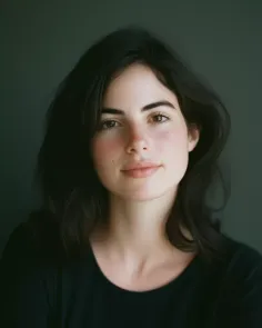 Woman with dark hair and a black shirt against a dark background