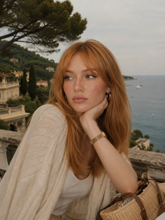 Woman with red hair and freckles looking out over a sea view