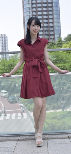 Woman in a red dress standing on a bridge overlooking a city street