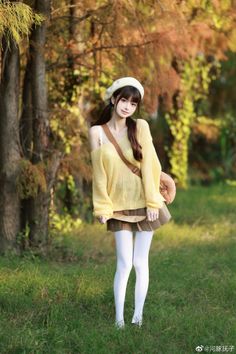 Woman with pigtails and a beret wearing a yellow sweater and pleated skirt outdoors