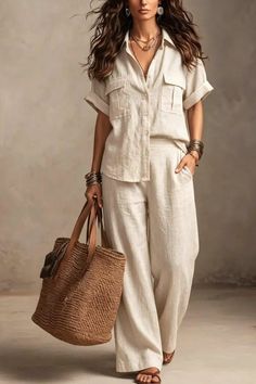 Woman in a light linen shirt and wide-leg pants holding a straw bag