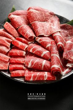 Close up of thinly sliced raw beef with marbling on a dark plate