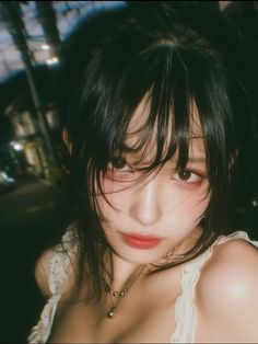 Woman with dark hair and a lace top in a dark setting