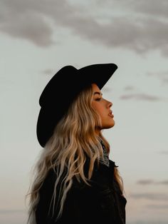 Woman in a cowboy hat and bandana looking up at the sky