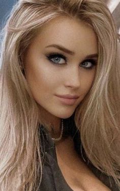 Woman with blonde hair and blue eyes wearing heavy eye makeup and a necklace