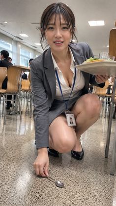 Woman in a business suit squatting to pick up a spoon in a cafeteria