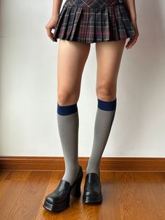Person wearing a plaid skirt, knee high socks, and platform shoes indoors