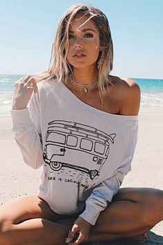 Woman with blonde hair wearing an off-shoulder top on a beach