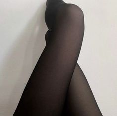 Person wearing black tights with legs crossed against a white background