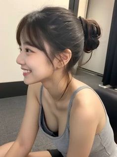 Woman with a messy bun and bangs wearing a gray tank top, smiling