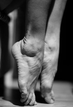 Close up black and white photograph of feet on tiptoes with dramatic lighting