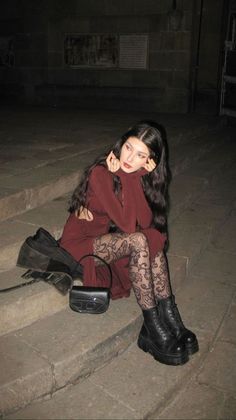 Woman with long dark hair sitting on stone steps at night