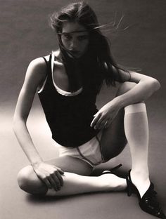 Woman in a tank top and underwear with high heels and white socks in a sitting pose