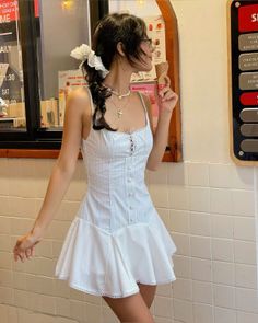 Woman in a white dress with braided hair holding an ice cream cone indoors