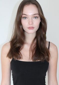 Woman with long brown hair and blue eyes wearing a black tank top