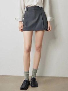 Person wearing a white shirt, gray mini skirt, gray socks, and black loafers