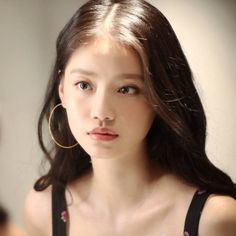Woman with long dark hair and hoop earrings in a black top