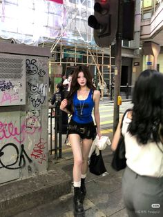 Woman in a blue tank top and black shorts walking on a city street