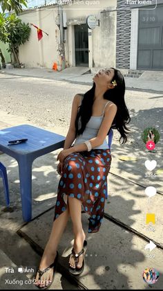 Woman with long dark hair and a polka dot skirt sitting outdoors