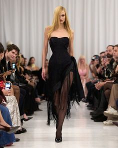 Model in a black fringe dress walking down a runway