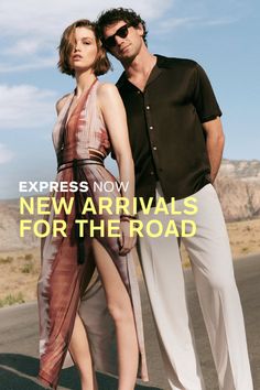 Two people posing on a desert road with mountains in the background