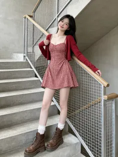 Woman in a red plaid dress and cardigan standing on concrete stairs