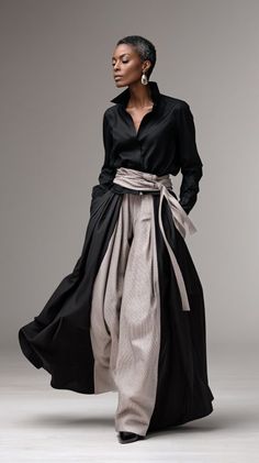 Woman in a black shirt and wide leg pants with a sash belt in a studio