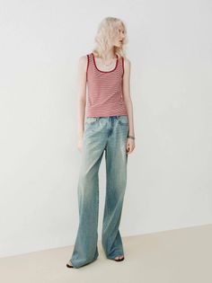 Woman with blonde hair wearing a red striped top and wide leg jeans
