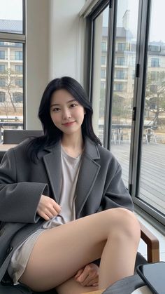 Woman with long black hair wearing a gray blazer and shorts indoors