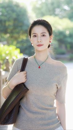 Woman in an off-shoulder top with a brown bag and red earrings outdoors
