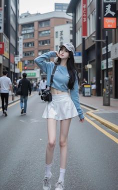 Woman in a cropped top and pleated skirt with a camera on a city street