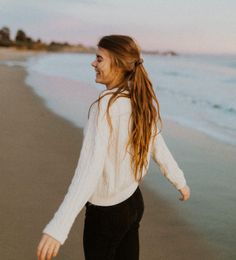 Woman with long hair in a ponytail walking on a beach at sunset