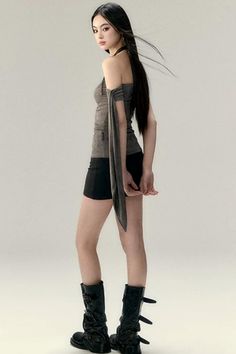 Woman with long dark hair wearing a strapless top, black shorts, and boots