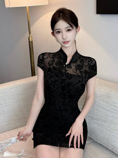 Woman in a black sheer floral dress with a high collar, holding a fan
