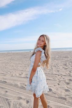 Young woman with blonde hair in a floral dress on a sandy beach