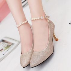 Pair of glittery gold high heels with pearl ankle straps